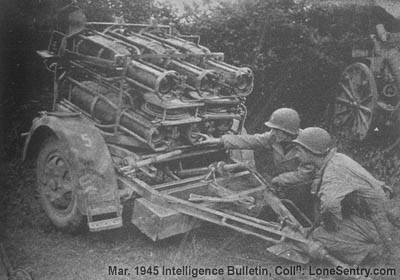 [U.S. soldiers inspect a captured 28/32-cm Nebelwerfer 41. The weapon is loaded, but electrical leads are not connected to the bases of the rocket motors. Note the box (shown open) which protects the sight.]
