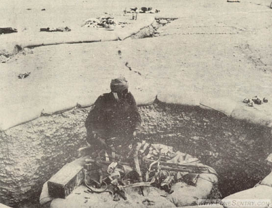 [This Indian soldier is inspecting captured Axis small arms and web equipment in an Omar fortification. Notice that the top of this position is flush with the surface of the ground.]